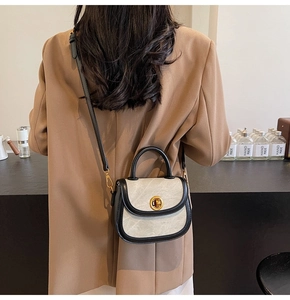 Retro mini saddle bag in beige and black with a golden clasp on a model’s shoulder