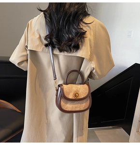 Close-up of vintage brown leather saddle bag with beige panels on trench coat model