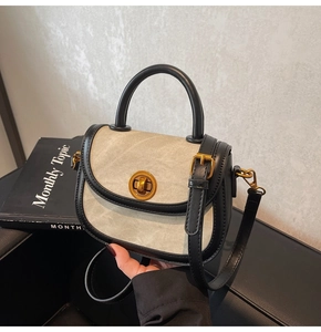 Detail of contrast color saddle bag featuring gold cylindrical lock and leather handle
