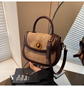 Detailed shot of retro saddle bag with gold buckle and brown leather stitching accents