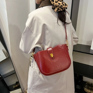 Minimalistische tiefrote glänzende Lederbeuteltasche mit goldenem Drehverschluss