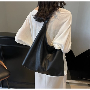 Detailed view of large black soft leather tote bag showing slouchy texture and fit on shoulder