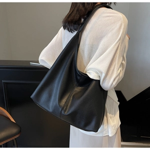 Close-up of the soft black lychee grain leather texture and wide strap of the tote bag