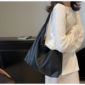 Close-up of black lychee texture hobo bag worn by a model for a chic lifestyle look