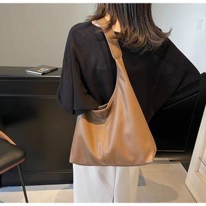 Brown lychee grain leather hobo bag with wide strap shown on shoulder from behind