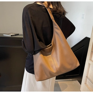 Detail view of coffee brown tote bag in pebbled leather with minimalist shoulder strap