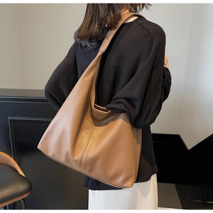 Brown leather tote bag with pebble texture shown worn on shoulder by a model