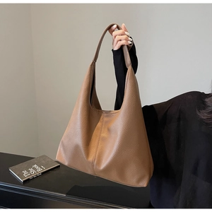 Detail of caramel brown pebbled leather hobo bag with wide shoulder strap and soft texture