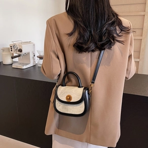 Retro small saddle crossbody bag with beige texture and black trim on coffee shop background