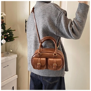 Close-up of brown vintage leather bag showing front buckle pockets and textures