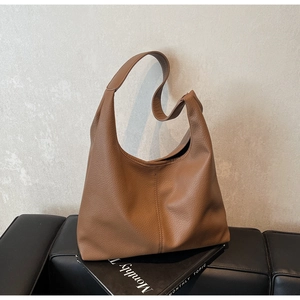 Detailed macro view of the brown lychee-patterned leather and stitching on the hobo bag
