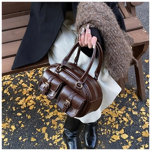 Close-up of retro brown PU leather bowling bag with twin buckle pockets in autumn setting