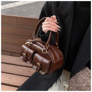 Detail of dark brown leather handbag with vintage metal buckles and small front pockets