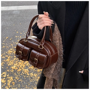 Detail of a chocolate brown retro bowling bag with two buckle pockets in autumn setting
