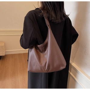 Detail of soft brown pebble leather tote bag shown on shoulder for daily commute style