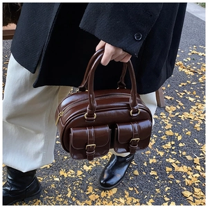 Outdoor shot of a vintage dark brown bowling bag held by a model on autumn leaves