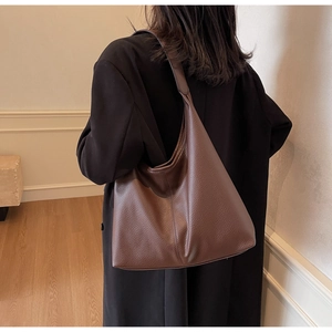 Close-up of brown litchi pattern leather shoulder bag on model for elegant style