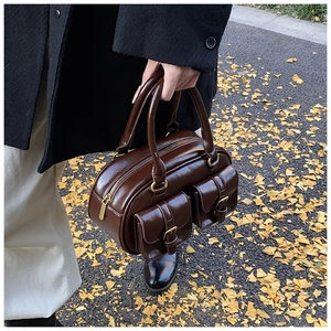 Detail of dark brown glossy leather bowling bag with front pockets on autumn background