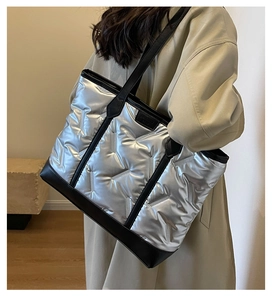 Detail of silver quilted tote bag with black handles showing the large capacity and texture