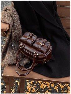 Detail of dark brown patent leather retro bowling bag against an autumn background