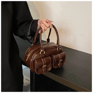 Detail of dark brown vintage bowling bag with front buckle pockets and gold hardware