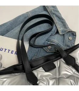 Close-up of metallic silver quilted tote bag with black leather straps and fashion label