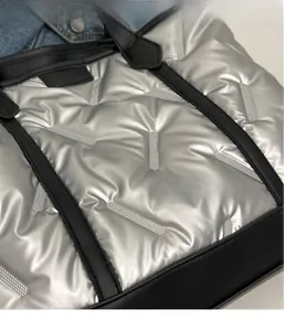 Close-up of silver quilted tote bag featuring metallic water-resistant fabric and black handles