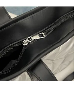Close-up of smooth silver metal zipper on black textured leather of the quilted tote bag
