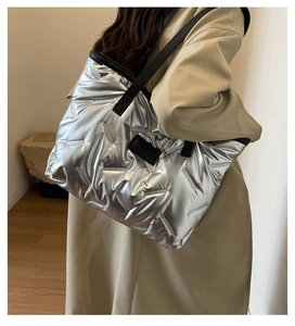 Détail du sac fourre-tout matelassé argenté avec sangles en cuir noir et étiquette