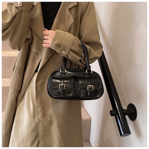 Detail of a black vintage bowling bag with shiny leather finish and gold buckles
