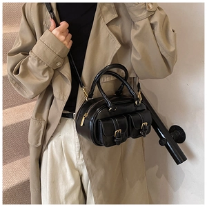 Close-up of black retro bowling bag with gold buckle pockets on a khaki trench coat