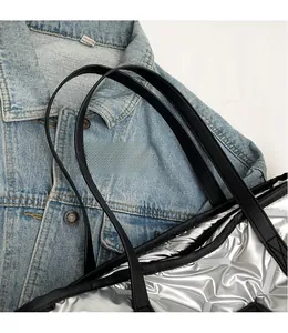 Détail du sac fourre-tout argenté matelassé avec finition métallique et bandoulière noire
