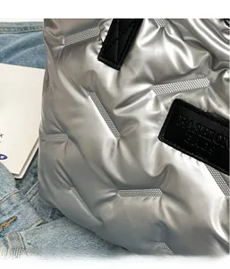 Détail de la texture du sac cabas matelassé argenté avec étiquette de mode cousue