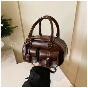 Detail of dark brown glossy leather bowling bag featuring front flap pockets and gold hardware