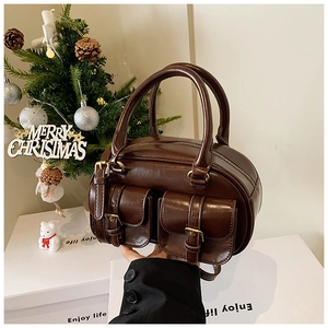 Detail of dark brown vintage handbag featuring twin front pockets and gold buckle accents