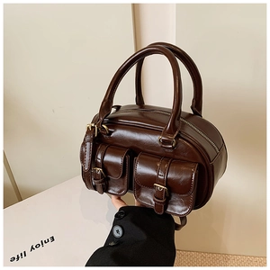 Detail of dark brown retro bowling bag showing polished leather texture and metal buckles