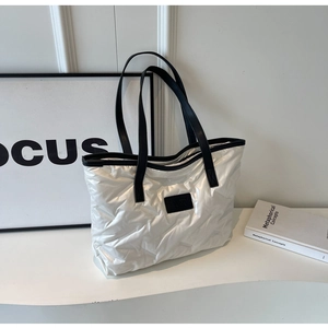 Détail d'un sac cabas argenté matelassé avec texture métallique et lanières noires