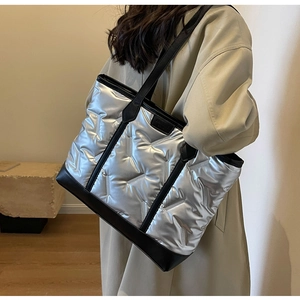 Silver quilted tote bag with black straps and fashion label shown on model's shoulder