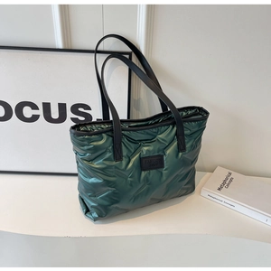 Détail du sac fourre-tout matelassé vert foncé avec poignées et logo en cuir