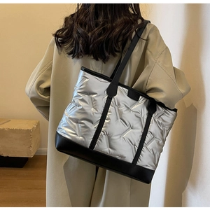 Close-up of silver quilted tote bag with black leather straps and metallic finish