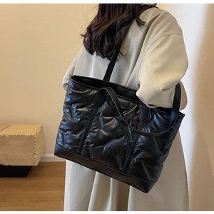 Close-up of black quilted tote bag with glossy cloud-like texture and dual straps