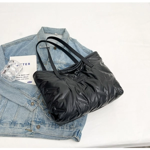 Vue détaillée du sac cabas matelassé noir avec étiquette sur une veste en jean
