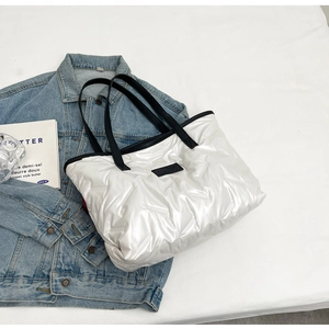 Gros plan sur le sac fourre-tout matelassé blanc avec logo noir et anses tissées