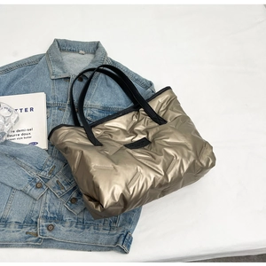 Détail du sac cabas matelassé doré champagne avec sangle noire sur fond décontracté
