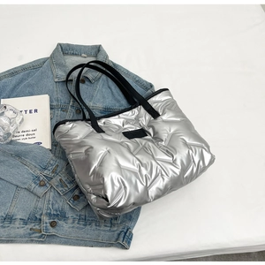 Détail d'un sac cabas argenté matelassé avec surpiqûres en V sur un tissu en denim