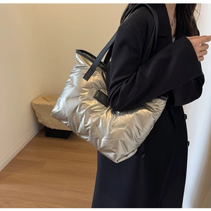 Sac cabas argenté matelassé avec anses noires porté par un mannequin en intérieur