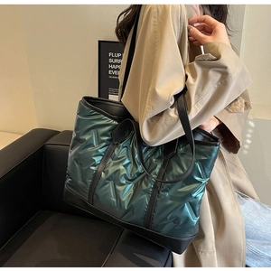 Metallic green quilted tote bag shown on shoulder in a modern minimalist home interior