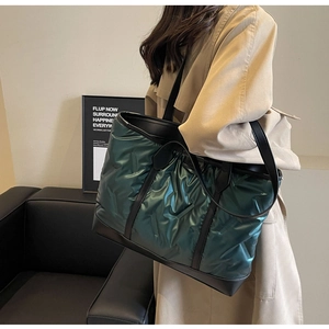 Detail of dark green quilted tote bag with black leather straps on a minimalist background
