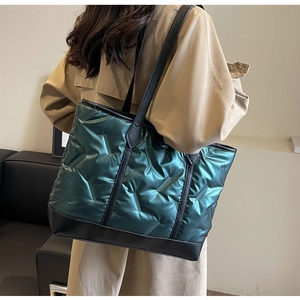 Detail of dark green quilted tote bag with metallic finish and black leather base