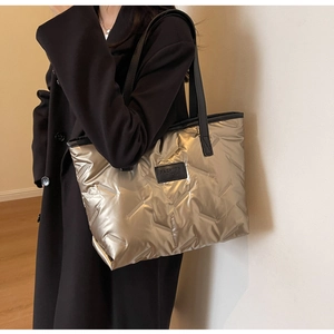 Détail du sac cabas matelassé doré avec bandoulières noires et étiquette de mode